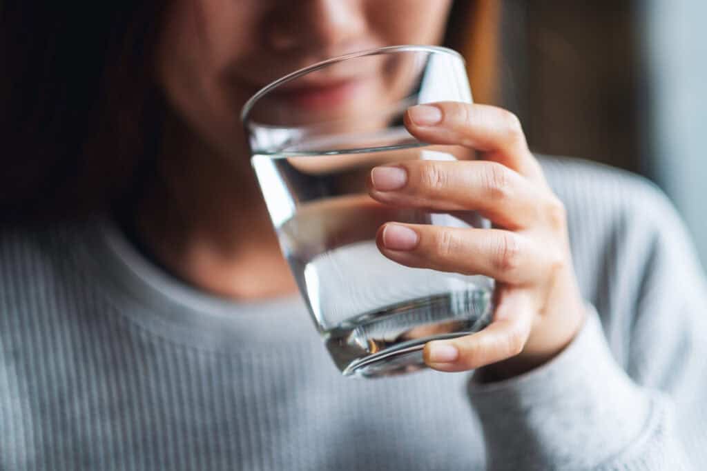 Person holding a clear glass of water.