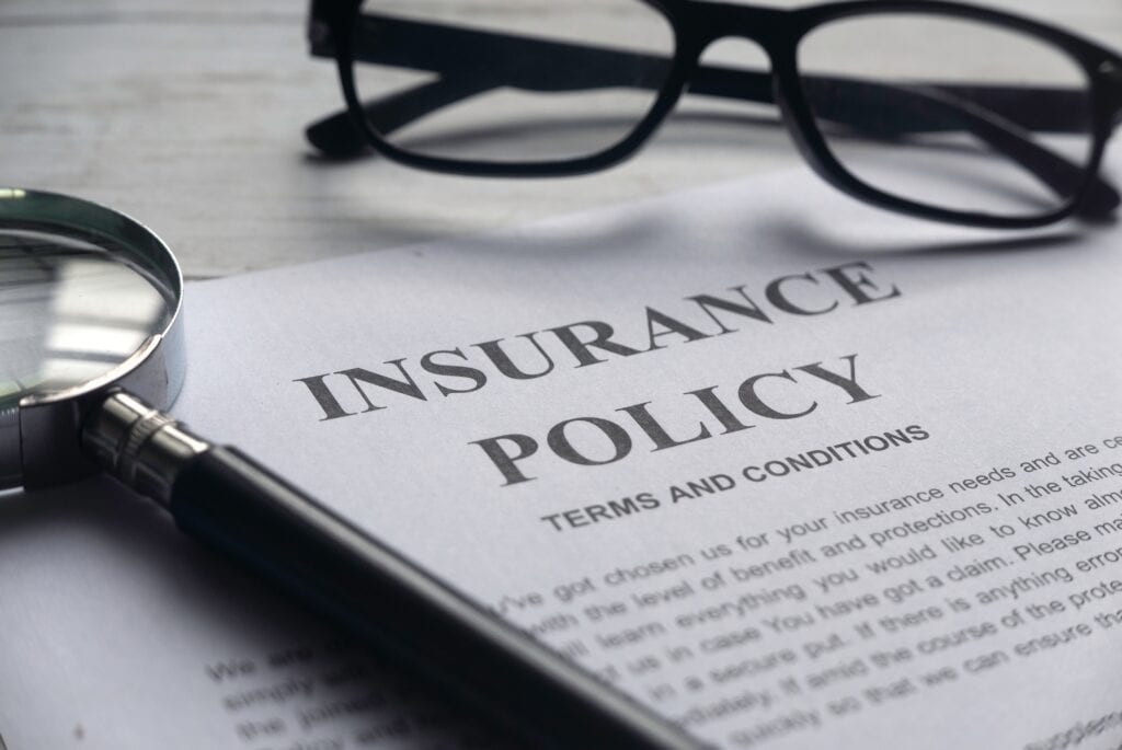 Insurance policy document with magnifying glass and glasses.