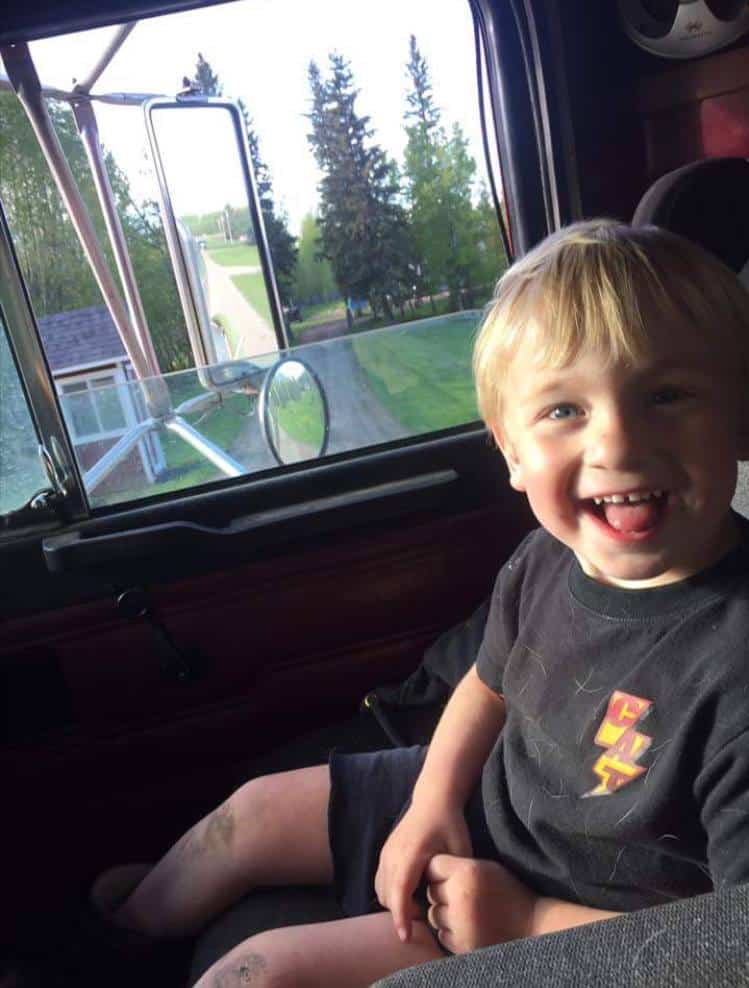 Smiling child sitting in a truck cab.